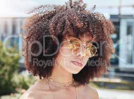 face of a beautiful young african american woman with a curly afro wearing sunglasses outside. Cool, trendy, hipster woman wearing yellow sunglasses enjoying the day outside in summer. Stylish woman