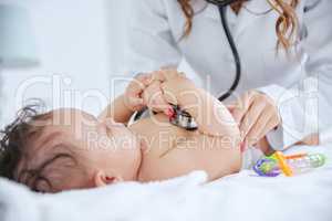 Time for her monthly checkup. Shot of a doctor listening to the heartbeat of a little baby using a stethoscope.