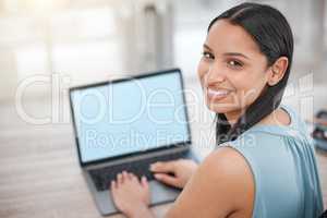 Smiling young businesswoman typing on her laptop keyboard, looking over her shoulder. Hispanic powerful business professional sending emails from her laptop online. Confident businesswoman at work