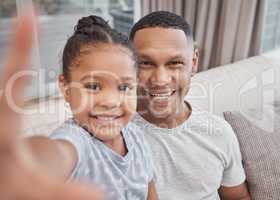 Handsome young mixed race man and his cute daughter taking a selfie photograph at home. Father and his girl child bonding and taking pictures in the living room. a single parent and his female kid