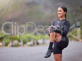 Active and fit young mixed race woman stretching her leg during outdoor exercise. Smiling, toned hispanic athlete getting ready to run in the morning. Routine sports and physical activity are healthy