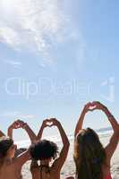 These girls have got the love. a group of friends with their hands in the air creating heart shapes.