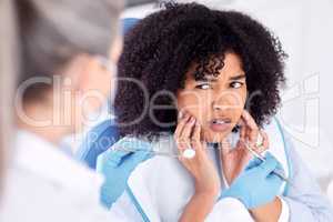 .. Shot of a young woman experiencing pain and anxiety while having a dental procedure performed on her.