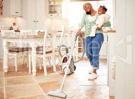 A single mom can do it all. Full length shot of an attractive young woman vacuuming and making a phonecall while carrying her daughter at home.