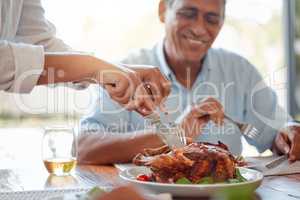 We cant wait to dig in. an unrecognizable person cutting a chicken at the the dinner table at home.