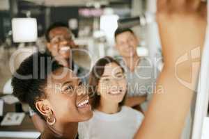 Happy african american business woman leader writing on board explaining idea and thoughts while brainstorming with colleagues. Diverse colleagues discussing ideas while collaborating on project