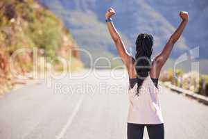 Active woman from the back cheering with arms outstretched outdoors. Proud athlete celebrating victory and accomplishment after run or jog. Inspired and motivated to reach fitness and wellness goals