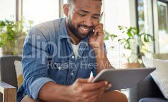 Handsome bachelor using a stylus to write on his digital tablet. Happy young man using his wireless digital device. Man relaxing at home reading an ebook on his tablet. Young man relaxing at home