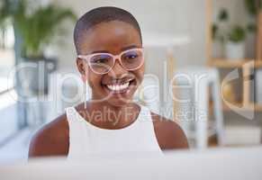 Young trendy african businesswoman wearing glasses and working on computer in an office. One female only browsing and planning online. Confident happy entrepreneur completing deadlines for her startup