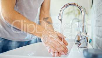 One unknown man washing his hands in a bathroom at home. Unrecognizable male using soap to kill bacteria and prevent the spread of viruses in a basin at home in his apartment