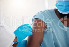 Hand of a doctor holding a needle with the vaccine. The covid vaccine will cure my patients. African american patient being injected during a checkup. Patient wearing a mask during a consult