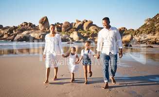 Happy young african american family with two children holding hands and having fun while walking along beach. Loving parents enjoying vacation with cheerful little daughter and son