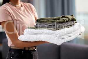 Freshly washed. an unrecognizable woman carrying a freshly washed and folded pile of linen while spring cleaning at home.