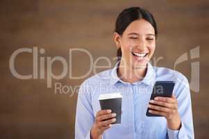 Smiling mixed race businesswoman isolated against a brown background with copyspace and using a cellphone to browse the internet during a coffee break. Hispanic professional laughing at social media