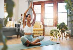 Stay grounded and focused. Shot of a sporty young woman meditating at home.