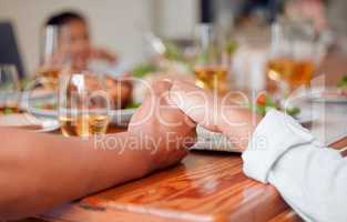 If we have each other, we have everything. two unrecognizable people holding hands at the dinner table at home.