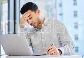 The lines are starting to blur. a young businessman massaging his head as he experiences a headache.