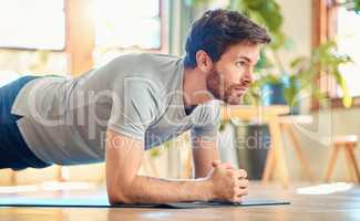 One fit young caucasian man doing elbow plank hold bodyweight exercise while training at home. Focused guy challenging himself to gain muscle, enhance upper body, core strength and increase endurance during workout