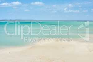 Copyspace at the sea with a blue sky and mountain background above the horizon. Calm blue ocean water at an empty beach shore. Peaceful scenic coastal landscape for a relaxing and zen summer getaway