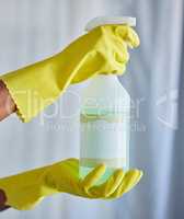 Closeup of a woman holding a cleaning product while tidying her apartment with copyspace. A busy domestic cleaner wearing latex gloves and holding an unlabelled organic agent, hygienic and fresh