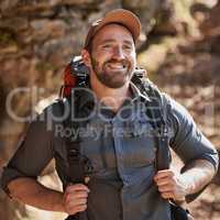 Happy caucasian man with beard carrying a backpack and hiking alone in the mountains during the day. Smiling fit and active man enjoying nature while exercising and exploring. Staying active on adventures