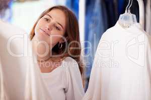 Im out for a little retail therapy. an attractive young woman checking an item of clothing in a store.