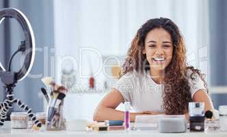 One hispanic woman recording a makeup tutorial for her beauty blog with her phone while sitting at home. African american female influencer live streaming her cosmetic review and recommendation online