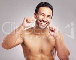 Closeup young mixed race man shirtless in studio isolated against a grey background. Hispanic male using dental floss. Taking caring of mouth and oral hygiene to promote healthy teeth and gums