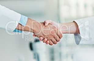 Lets advance together. Closeups shot of two unrecognisable scientists shaking hands in a lab.