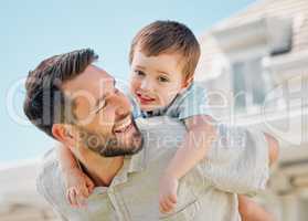 Happy caucasian father carrying playful little son on his back for piggyback ride in garden or backyard outside. Smiling parent bonding with adorable child. Kid enjoying relaxing free time with dad