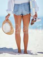 Rearview beautiful young caucasian woman relaxing on the beach. Enjoying a summer vacation or holiday outdoors during summer. Taking time off and getting away from it all. Spending the day alone