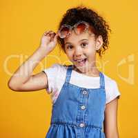 Studio portrait mixed race girl wearing funky sunglasses Isolated against a yellow background. Cute hispanic child posing inside. Happy and carefree kid with an imagination for being a fashion model