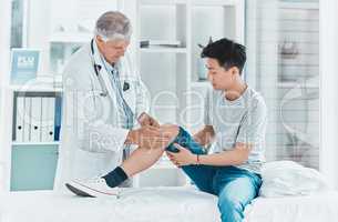 Some injuries are undetectable. Shot of a mature doctor checking his patients knee for injury.