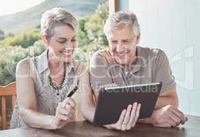 We just love a good pensioners discount. Shot of a mature couple sitting together while using a digital tablet and a credit card.