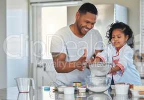 Baking is an opportunity to share quality time with a loved one. Shot of a father baking with his daughter at home.