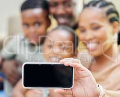 Say cheese. an unrecognisable family sitting on the sofa together at home and taking selfies on a cellphone.