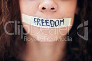You cant stop me from speaking my mind. Closeup shot of an unrecognisable woman with tape on her mouth that has the word freedom written on it.