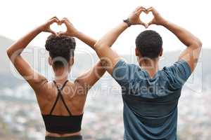 Rearview fit african american couple making heart shapes with their hands while exercising outdoors. Young athletic man and woman promoting health and fitness outside. They love to workout together