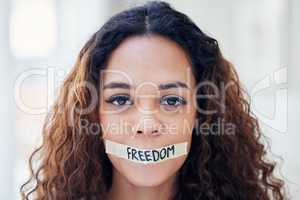 We realise the importance of our voices when we are silenced. Portrait of a young woman with tape on her mouth that has the word freedom written on it.