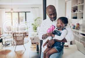 Fatherhood is a true blessing. a happy father feeding and spending time with his infant daughter at home.
