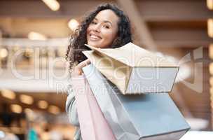 Portrait beautiful mixed race woman standing in a mall while out on a shopping spree. Young hispanic woman carrying bags, spending money, looking for sales and getting in some good retail therapy