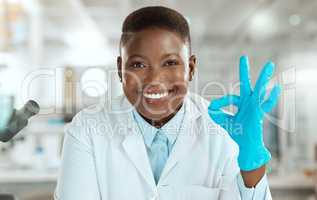 Ive got it from here. Shot of an attractive young scientist sitting alone in her laboratory and making an okay sign.