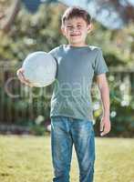 Happy as could be. Shot of an adorable little boy holding a soccer ball outside.