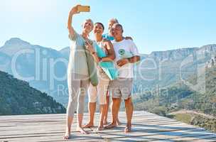 Group of active seniors posing together for a selfie or video call on a sunny day against a mountain view background. Happy diverse retirees taking photo after group yoga session. Living healthy and active lifestyles