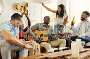 This is a song about friendship. Shot of a man playing the guitar while sitting in a living room with his friends.