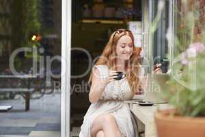 Online shopping no matter where she goes. Shot of a young woman making card payments at a cafe.