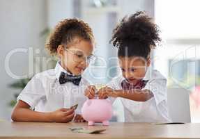 Get in there. two adorable little girls dressed as businesspeople sitting in an office and depositing money into a piggybank.