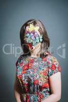 Young woman wearing mask against a grey background in studio. Young woman wearing mask against a grey background in studio.