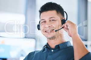 Portrait of one happy hispanic call centre telemarketing agent talking on a headset while working in an office. Confident friendly male consultant operating a helpdesk for customer service and sales support
