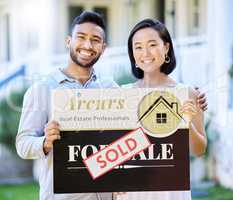 Its the start of a new journey. Shot of a young couple holding up a sold board outside their house.